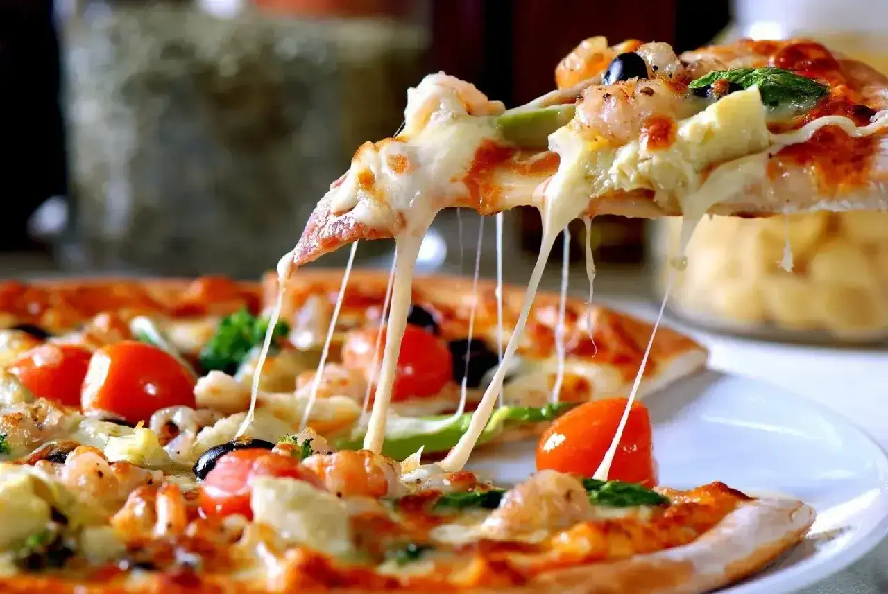 Rozciągający się ser z kawałka pizzy z krewetkami i pomidorkami. Idealne ciasto na pizzę z chrupiącymi brzegami.